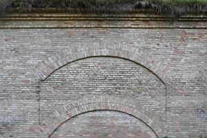 Very old brick stone wall of castle or fortress of 18th century. Full frame wall with obsolete dirty and cracked bricks photo