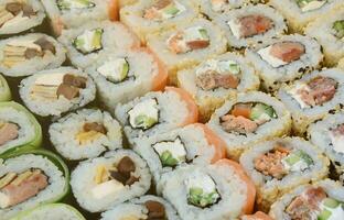 Close-up of a lot of sushi rolls with different fillings. Macro shot of cooked classic Japanese food. Background image photo