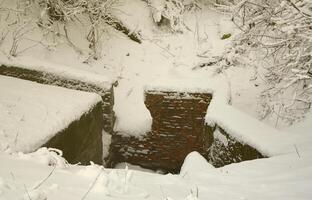 Underground bunker of old brick walls in winter after snowfall photo