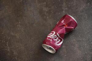 KYIV, UKRAINE - 4 MAY, 2023 Coca cola soft drink crumpled tin can with cherry flavour photo