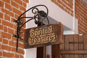 Old wooden sign on the background of the old castle walls, vintage image with Spiritual Treasures sign photo