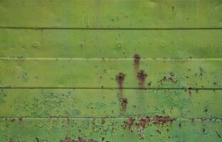 Texture of an old green metal wall with significant damage from exposure to unfavorable weather conditions and dampness photo