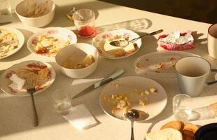platos sucios vacíos con cucharas y tenedores en la mesa después de la comida. concepto de final de banquete. platos sin lavar foto
