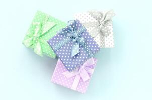 Pile of a small colored gift boxes with ribbons lies on a violet background. Minimalism flat lay top view photo