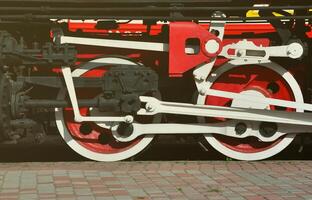 Wheels of the old black steam locomotive of Soviet times. The side of the locomotive with elements of the rotating technology of old trains photo