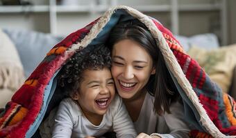 madre y niño son jugando debajo un cobija foto