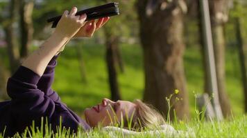 jovem mulher usando digital e livro em Relva dentro natureza video