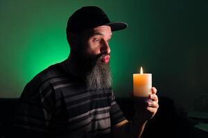 Bearded man holding a candle in his hand. Green background photo