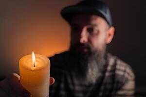 man holding a lit candle in his hand. photo