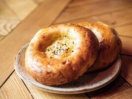 Tasty fresh tandoor bread on rustic wooden tabletop. Two tandoor flat bread cake with black sesame seeds on yellow wooden table background. National asian meal and food photo