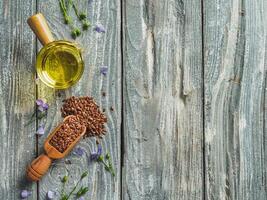 Flax seeds and flax oil. Brown linen seeds and flaxseed oil on old gray wooden background. Copy space. Top view or flat lay. photo