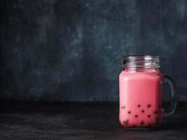 Homemade Milk Bubble Tea with Tapioca Pearls balls. Popular Taiwan bubble tea in glass mason jar with copy space for text. Bubble tea on dark background. photo