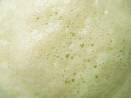 Green foam texture of matcha latte, close up photo