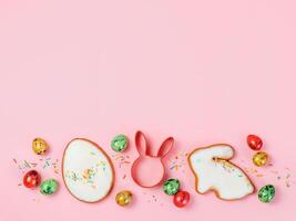 Easter cooking baking concept. Easter cookie cutter on pink pastel background. Happy Easter Day concept. Easter cookie cutters and cookies, colorful eggs over pink background. Copy space for text. Top view or flat lay photo