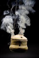 bowl of incense hanging smoke on black background photo