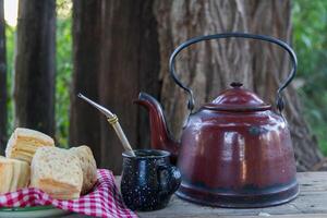 Mate and kettle with a plate of salty Argentine biscuits and yerba mate infusion photo