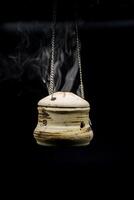 bowl of incense hanging smoke on black background photo