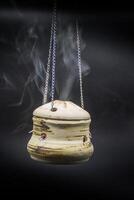 bowl of incense hanging smoke on black background photo
