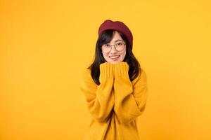 Portrait of cheerful 30s woman has shy satisfied expression, smiles broadly, wears yellow sweater, poses against yellow background. Ethnicity, emotions photo