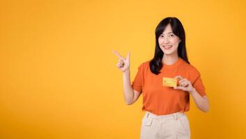 exitoso mujer de negocios en su 30, participación un crédito tarjeta y señalando dedo, haciendo seguro en línea actas en amarillo fondo. foto