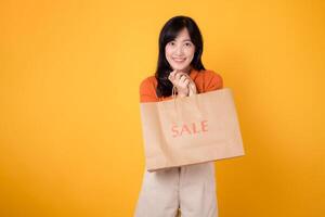 Excited shopper in her 30s showcases purchases with a happy smile isolated on yellow background. Fashionable and cheerful retail celebration. photo
