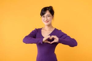 Portrait of an attractive and confident female model, her hand forming a heart shape, symbolizing love and happiness on Valentine's Day. photo