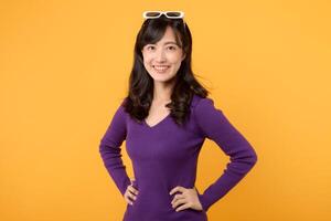 A positive and smart female model wearing a purple shirt and eyeglasses, a modern and confident student, radiates joy and elegance in a studio portrait against a vibrant yellow background. photo