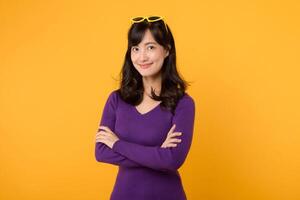 A confident and stylish businesswoman, wearing a purple shirt and sunglasses against a yellow background, exudes positivity and success with her cheerful smile and folded arms. photo