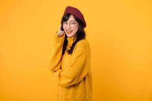 Portrait young asian woman 30s happy smile wearing yellow sweater and red beret showing thinking body language isolated on yellow background. photo