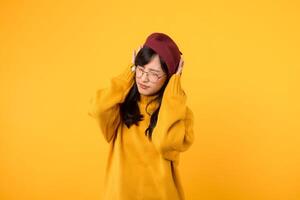 Noise stress getting to you. An upset lady, wearing a yellow sweater and red beret, seeks relief against a vibrant yellow backdrop. photo