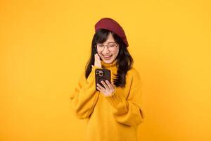 Surprised girl with smartphone, in a cheerful yellow setting, donning a stylish beret and eyeglasses. photo