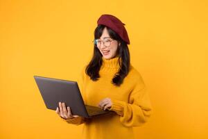 japonés, coreano, chino, y vietnamita etnias unido, utilizando un ordenador portátil en contra un elegante amarillo fondo, vistiendo un rojo boina y los anteojos. foto