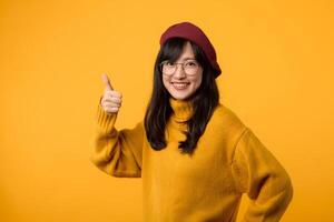 A fashionable woman in a yellow sweatshirt and beret, showing her positive attitude with a thumbs up and OK sign. photo