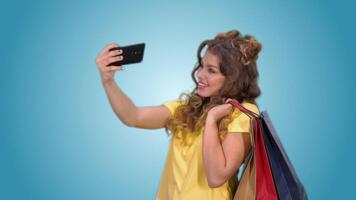 un contento hermosa niña en un amarillo camiseta hace un selfie participación brillante compras pantalones en pollos con verde pantalla video