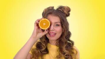 lindo jovem menina com grandes loiro cabelo poses com a laranja piscadelas e sorrisos enquanto olhando para dentro a Câmera. verde tela video