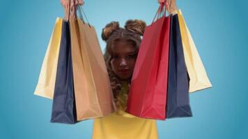 A beautiful young girl in a yellow vest holding multi-colored shopping bags and smiling. With green screen video