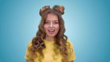 Beautiful young girl in a yellow shirt with long hair is surprised and smiling while looking into the camera. green screen video