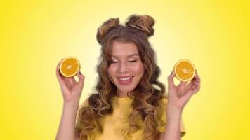 attractive girl in a yellow vest with long blond hair posing with oranges and smiling while looking into the camera. green screen video