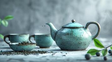 Teapot with cups, bowl of dry tea and leaves on white grunge background. Copy space. photo
