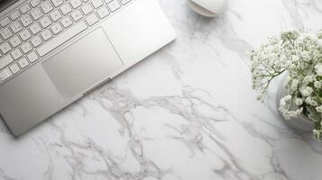 Notebook with keyboard with flowers in vase on white marble table. Top view of modern stylish workplace with laptop computer. Copy space. Flat lay. photo