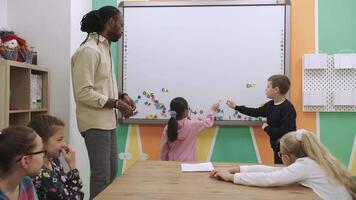 Kinder Schüler lernen Englisch durch Herstellung Wörter von Briefe auf ein magnetisch Tafel. Schule zum Kinder, Lehren Jugendliche, dazugewinnen Wissen, lernen das Sprache. video