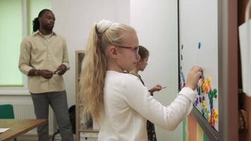 afrikanisch amerikanisch Lehrer unterrichtet Kinder Englisch mit ein magnetisch Tafel. Schule zum Kinder, Lehren Jugendliche, dazugewinnen Wissen, lernen das Sprache. video