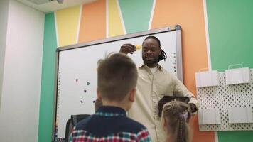 ett afrikansk amerikan lärare och en grupp av barn är studerar frukt och djur i de klassrum.skola för barn, undervisning tonåringar, få kunskap, lära sig de språk. video