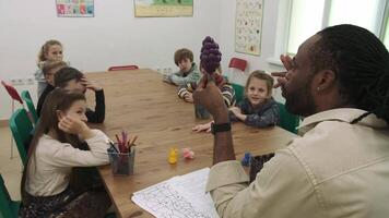 africano americano professor Ensinar frutas e animais para uma grupo do crianças. escola para crianças, ensino adolescentes, ganho conhecimento, aprender a linguagem. video