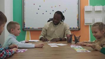 afrikanisch amerikanisch Lehrer und ein Gruppe von Kinder sind Lernen Zahlen während Sitzung beim das Tabelle im das Klassenzimmer.Schule zum Kinder, Lehren Jugendliche, dazugewinnen Wissen, lernen das Sprache. video