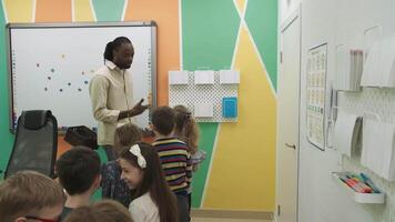 un africano americano insegnante insegna un' gruppo di bambini 10-12 anni vecchio, studiando animali e frutta.scuola per figli, insegnamento adolescenti, guadagno conoscenza, imparare il linguaggio. video