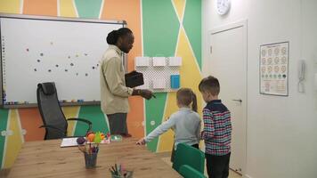 un africain américain prof et une groupe de les enfants sont en train d'étudier des fruits et animaux dans le salle de classe.école pour enfants, enseignement adolescents, Gain connaissance, apprendre le langue. video