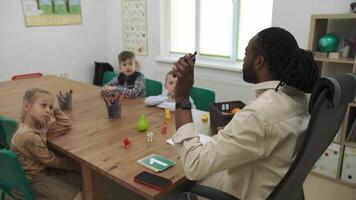un africain américain prof et une groupe de les enfants sont en train d'étudier des fruits et animaux dans le salle de classe.école pour enfants, enseignement adolescents, Gain connaissance, apprendre le langue. video