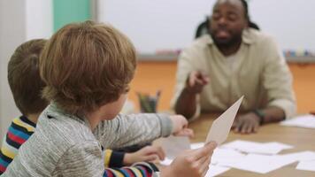 een Afrikaanse Amerikaans leraar geeft les een groep van kinderen getallen gebruik makend van flashcards.school voor kinderen, onderwijs adolescenten, krijgen kennis, leren de taal. video