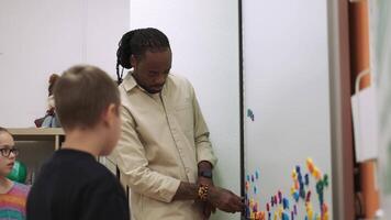 An African American teacher teaches a child using a magnetic board in the classroom.School for Children, Teaching Adolescents, Gain Knowledge, Learn the Language. video